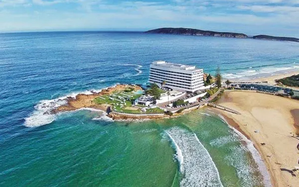 Beachfront hotel on a rocky outcrop with waves crashing against the shore