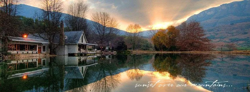 Sunset over a lake with mountains and a house reflection