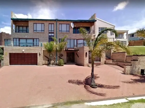 Modern twostory house with a large driveway and palm trees in front