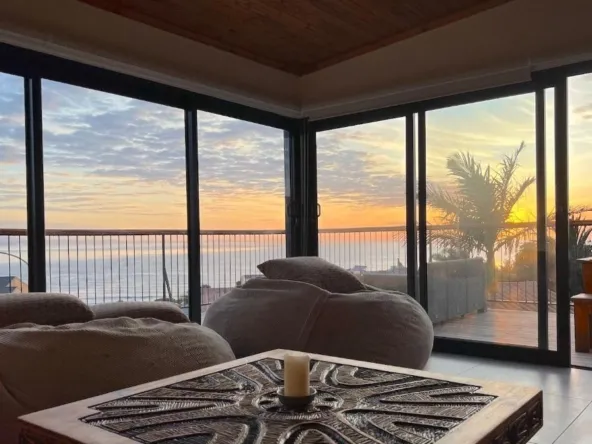 Living room with large windows ocean view and sunset sky