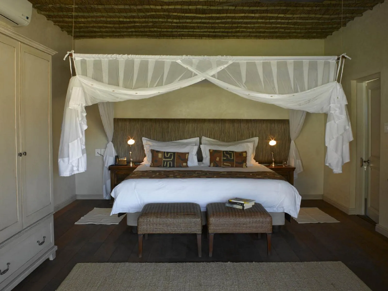 Bedroom with large bed canopy and bedside lamps on wooden floor