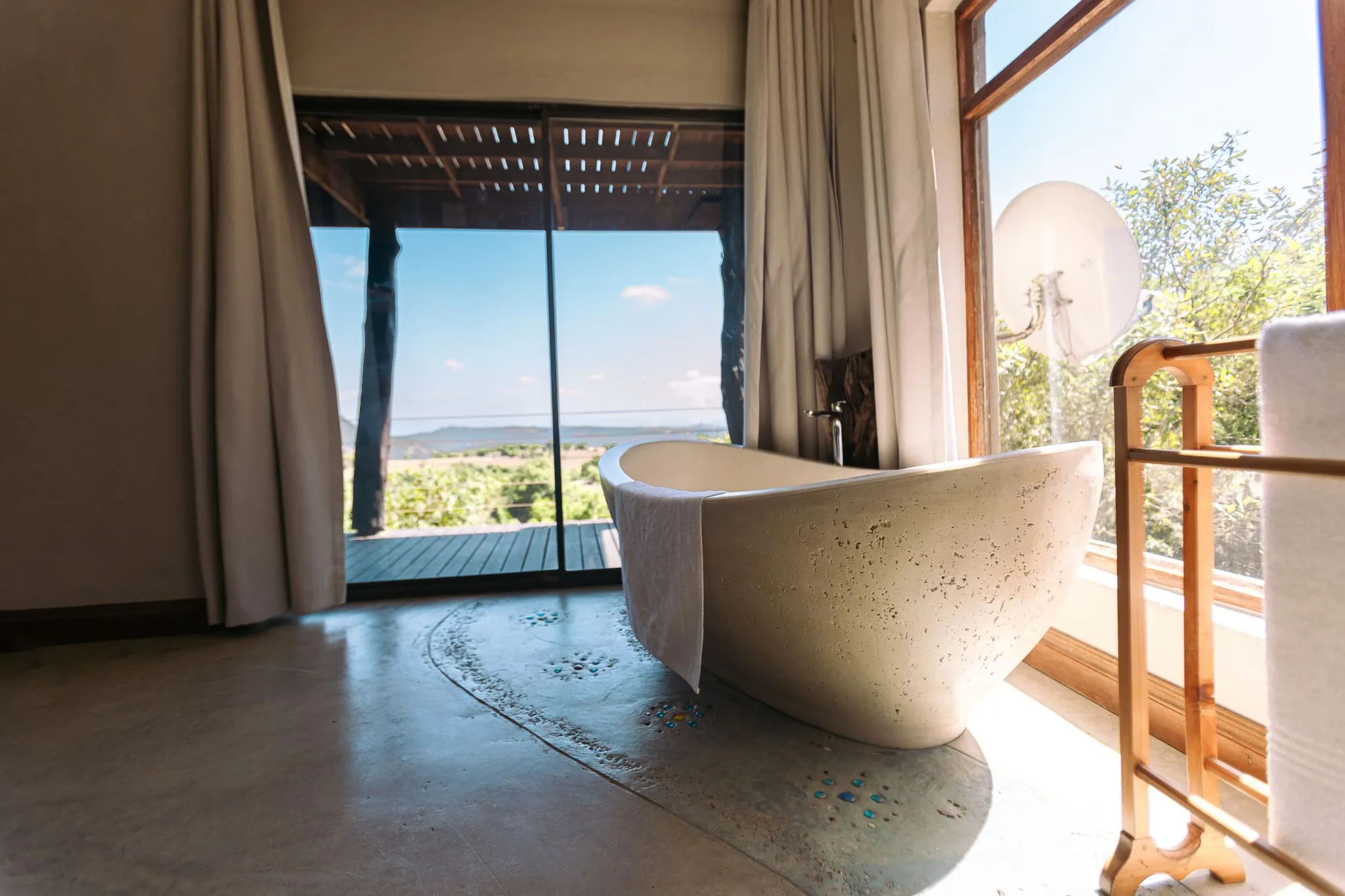 Freestanding bathtub in a room with open doors to a scenic outdoor view