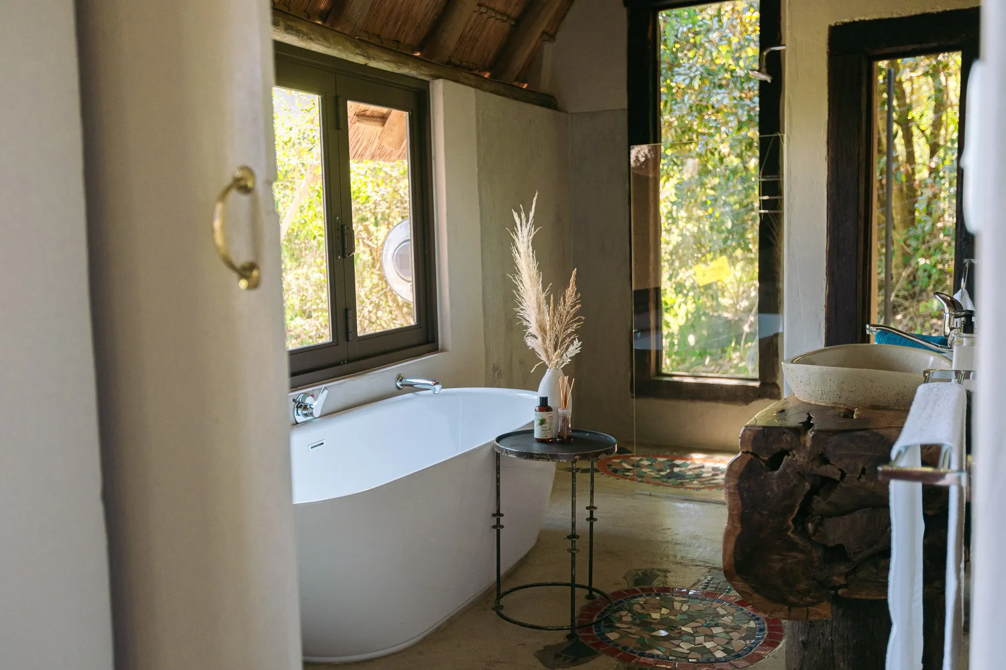 Freestanding bathtub in a rustic bathroom with large windows and natural decor