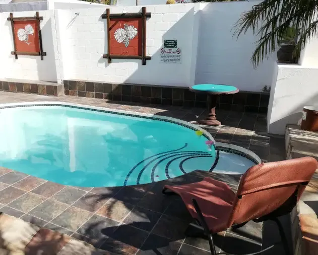 Swimming pool with lounge chair table and wall decorations in a backyard