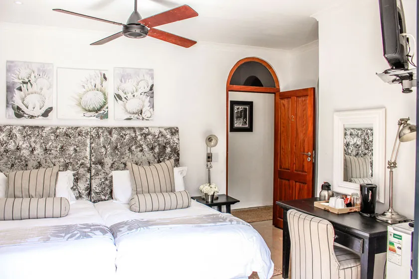 Cozy bedroom with two beds ceiling fan desk and wooden door
