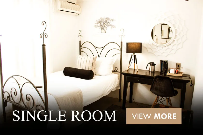 Single bed in a cozy room with a desk and mirror