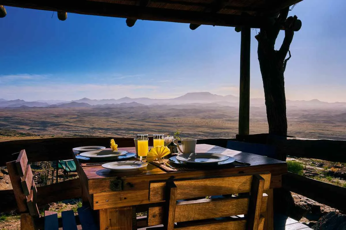 Wooden table with breakfast on a deck overlooking a vast mountainous landscape