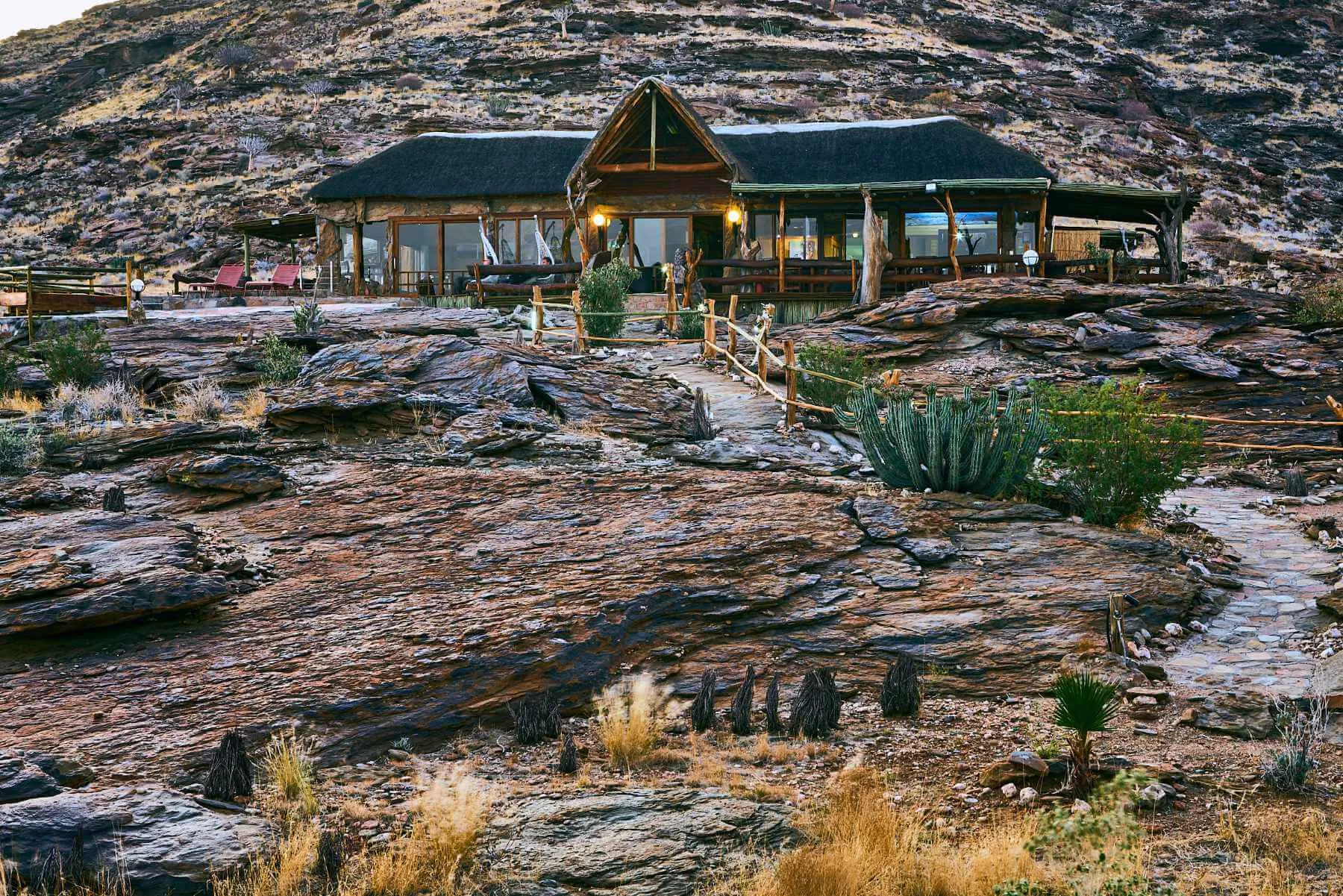 Wooden lodge on rocky terrain with mountains in the background