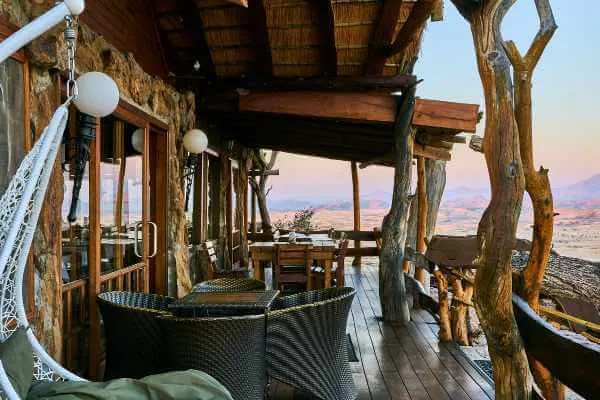 Wooden deck with wicker chairs overlooking a desert landscape at sunset
