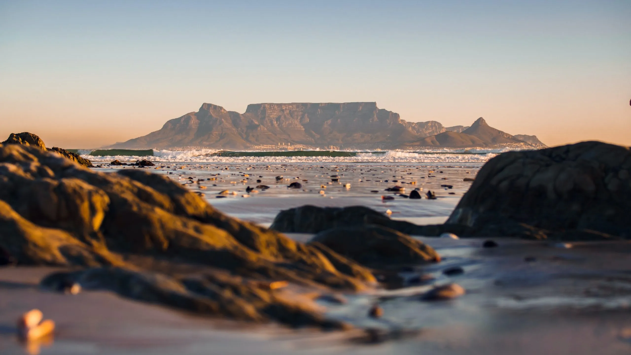 Rocky beach with distant view of Table Mountain at sunset