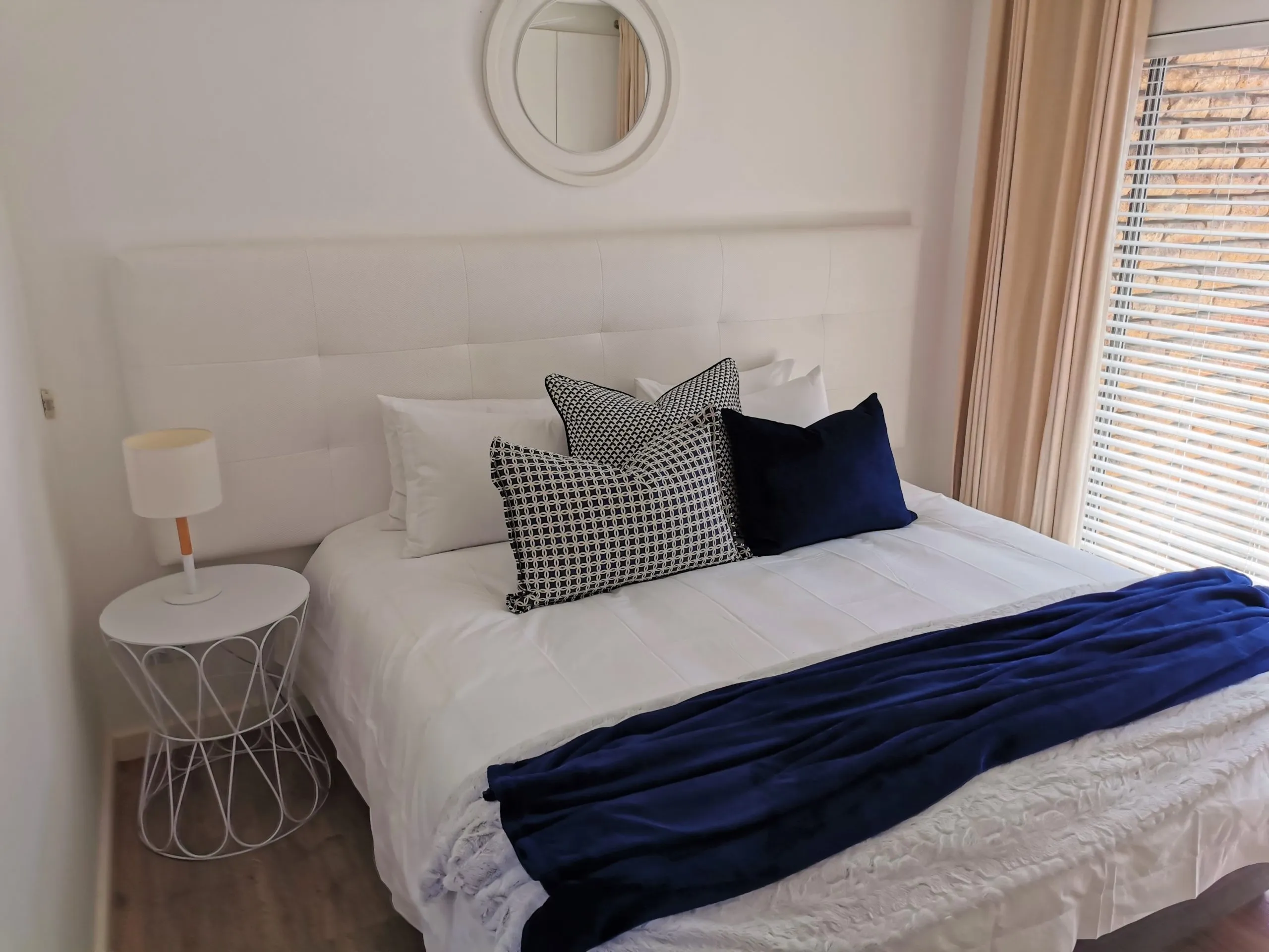 Modern bedroom with white bed blue and white pillows and bedside table with lamp
