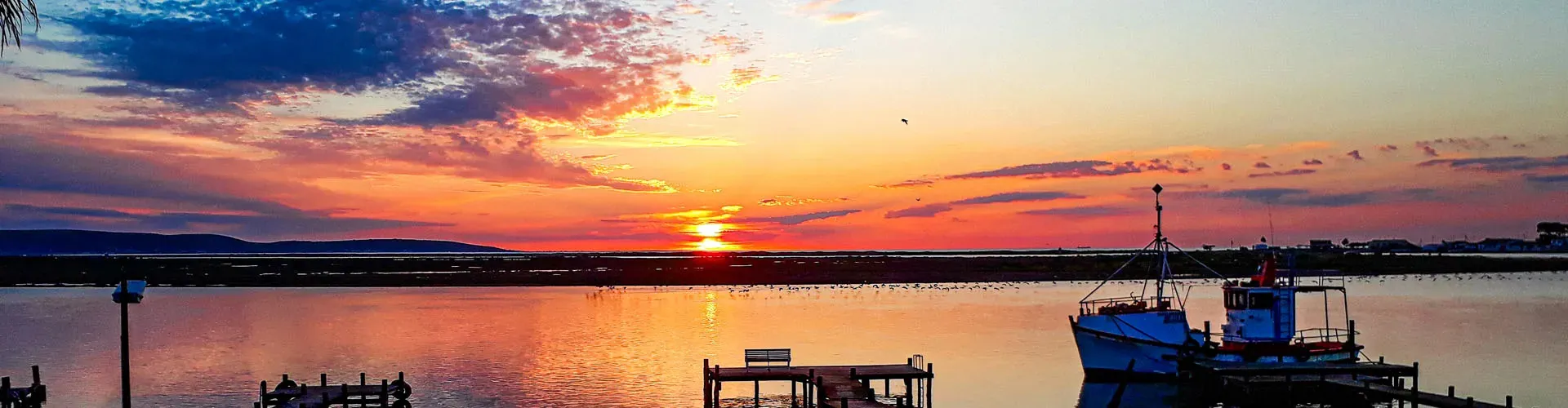 Sunset over a lake with a boat docked at a wooden pier