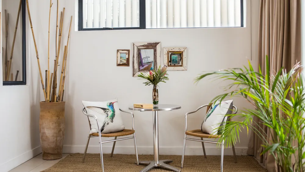 Two chairs with pillows around a small table in a modern living room