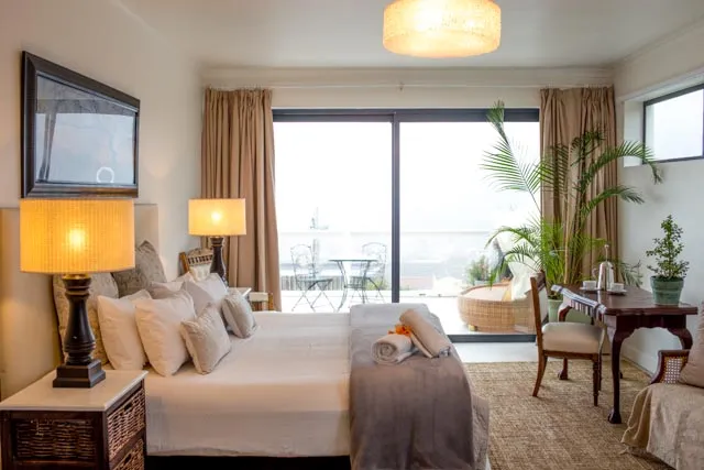 Bedroom with large bed lamps desk and sliding glass doors to a balcony