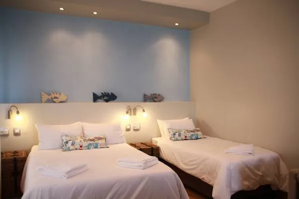 Two neatly made beds in a modern bedroom with wallmounted lights and fish decor