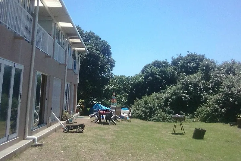 Backyard with lawnmower chairs and trees beside a twostory building