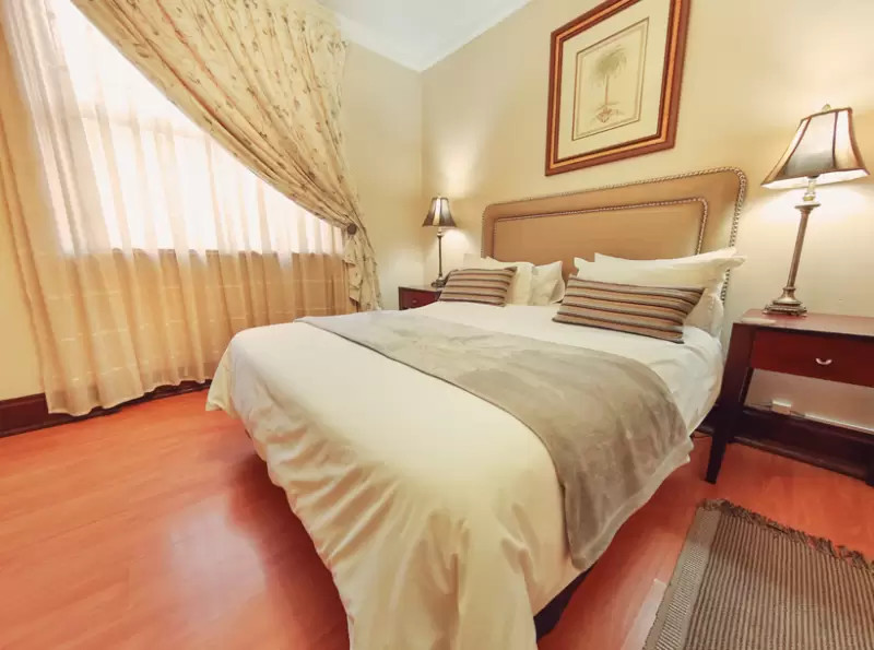 Cozy bedroom with large bed, bedside tables, and natural light from windows.