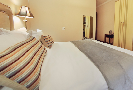 Cozy bedroom with a neatly made bed and bedside lamp.