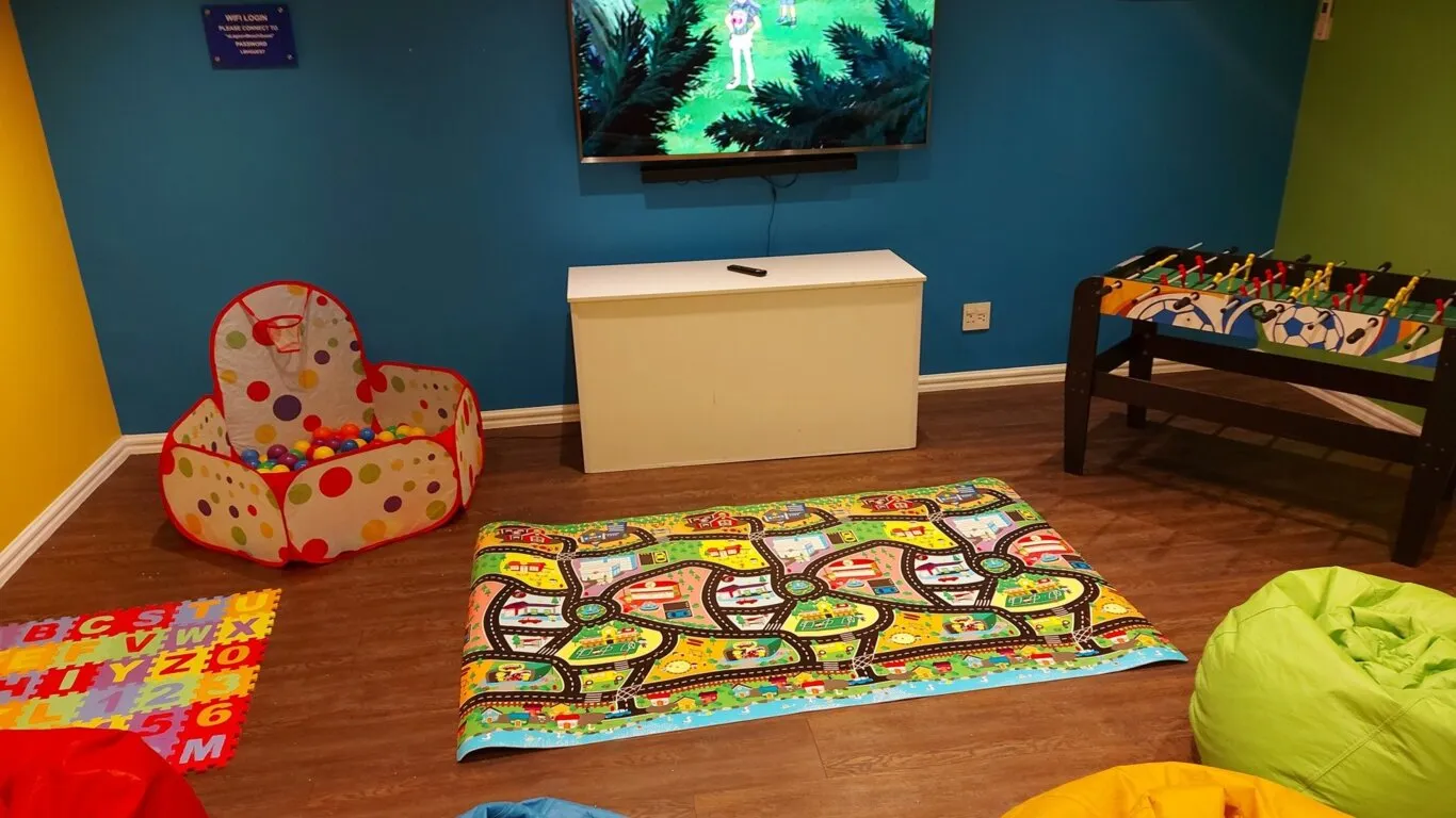 Childrens play area with toys TV and colorful mats on wooden floor
