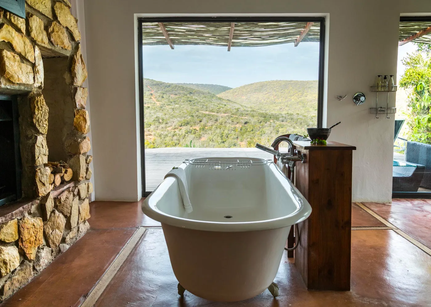 White bathtub in rustic room with large window overlooking scenic hills