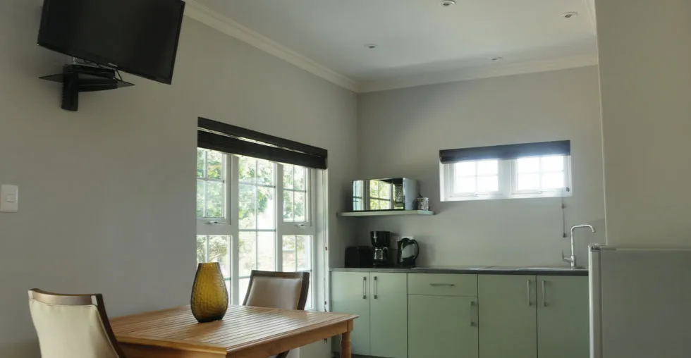 Kitchen with dining table chairs and mounted TV near window
