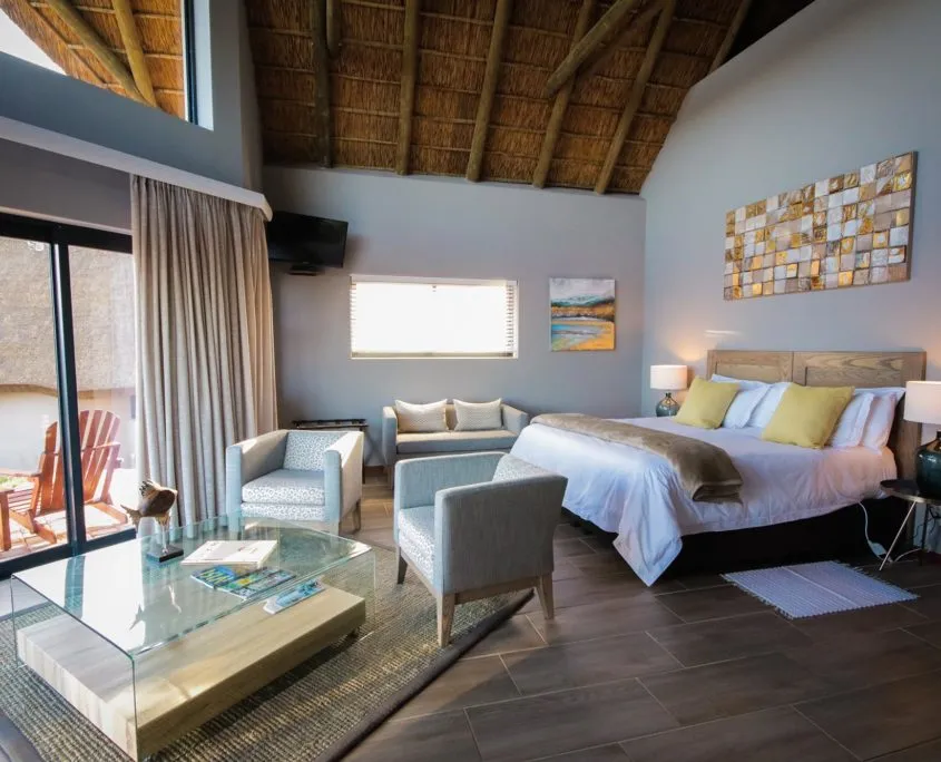 Cozy bedroom with large bed seating area and high thatched ceiling