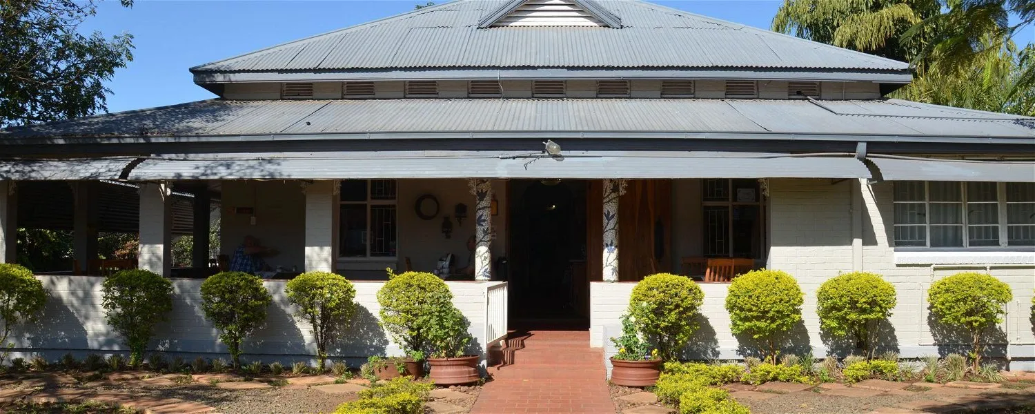 Large house with a veranda potted plants and a brick pathway