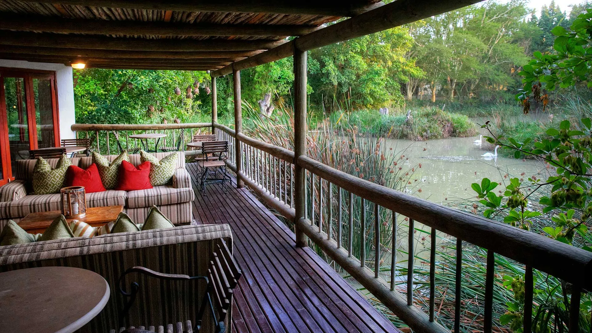 Wooden deck with seating overlooking a serene lake surrounded by greenery