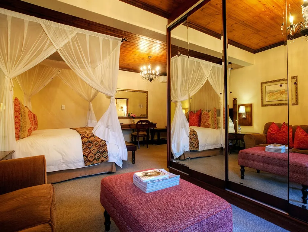 Bedroom with canopy beds mirrored closet and seating area with books