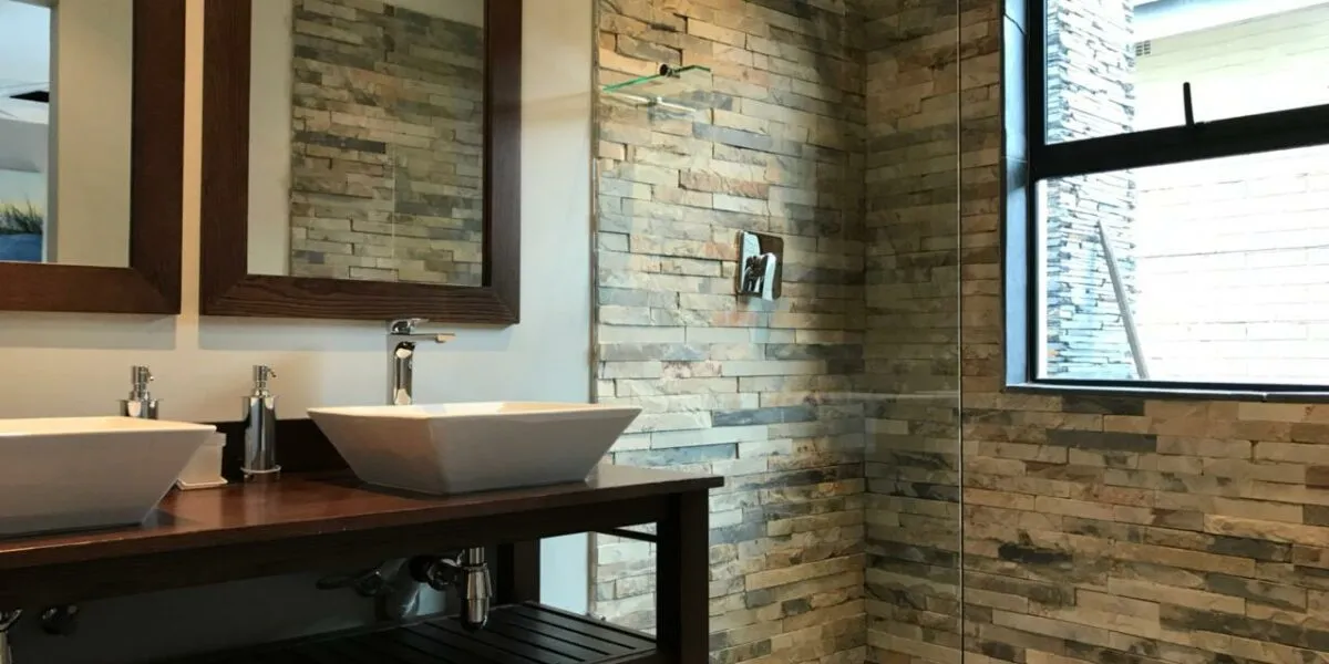 Modern bathroom with double sinks stone wall and large window