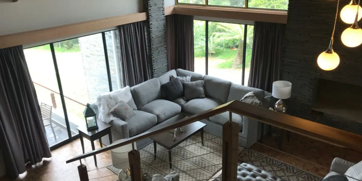 Modern living room with sectional sofa large windows and pendant lights