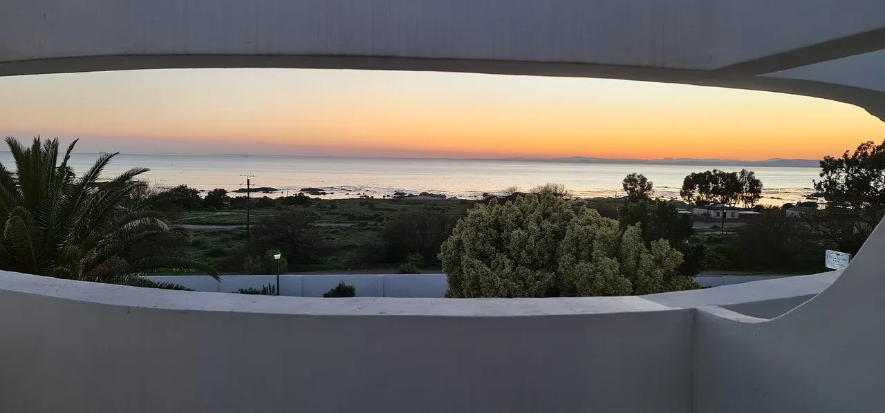 Sunset view from a balcony overlooking the ocean with palm trees