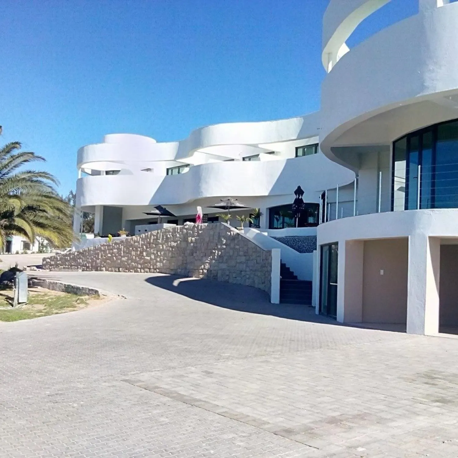 Modern white building with curved architecture palm trees and stone steps