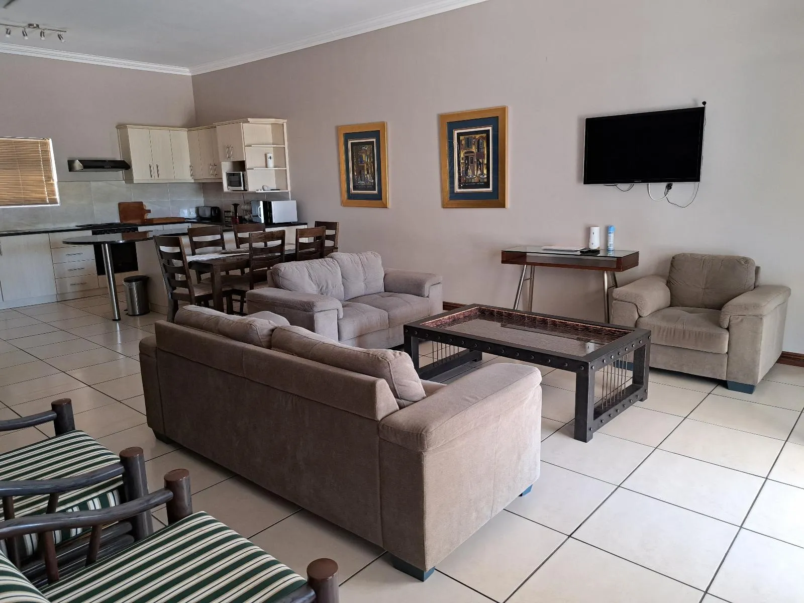 Living room with sofas coffee table TV and kitchen area in background