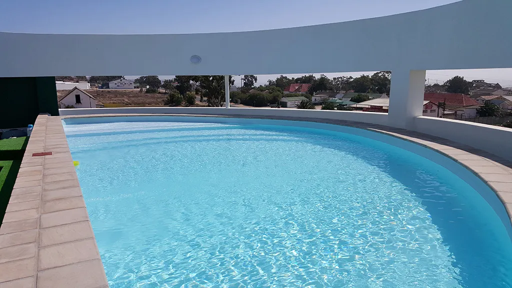 Curved swimming pool on a rooftop with a view of houses and trees