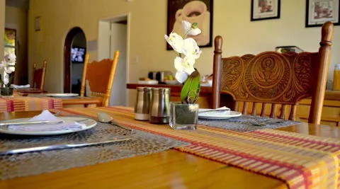 Wooden dining table with white orchids cutlery and placemats in a cozy room