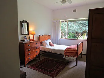 A tidy bedroom with a single bed wooden furniture and a window