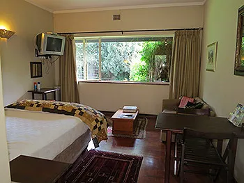 Cozy bedroom with a bed TV window view and wooden furniture