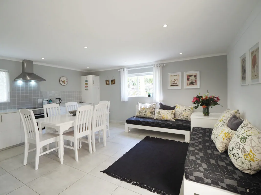 Bright kitchen and living area with white furniture and decorative pillows