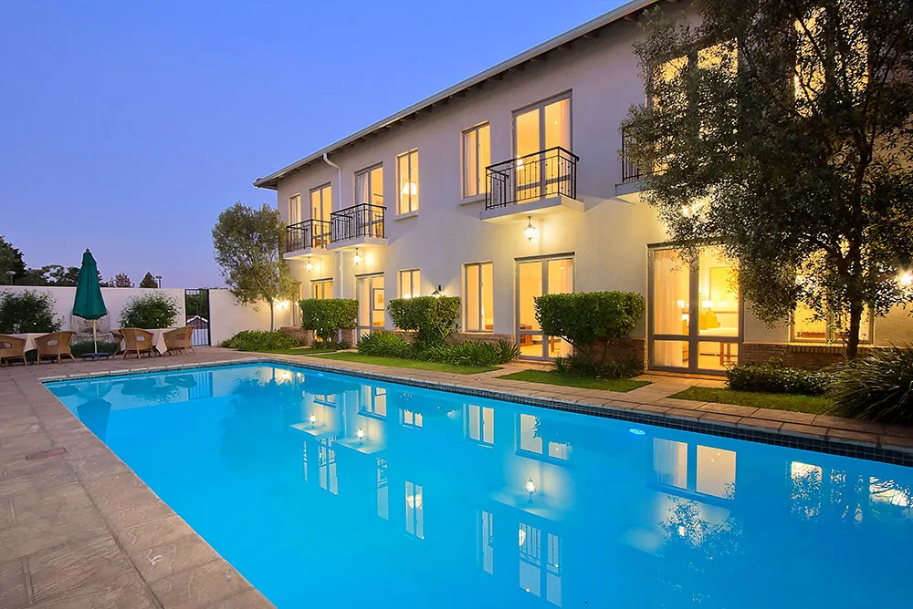 Modern house with lit windows and a swimming pool at dusk