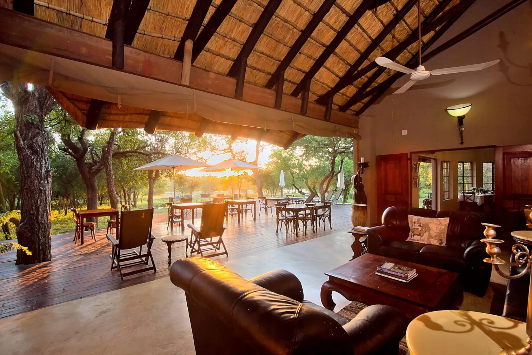 Cozy lounge with outdoor seating area under a thatched roof at sunset