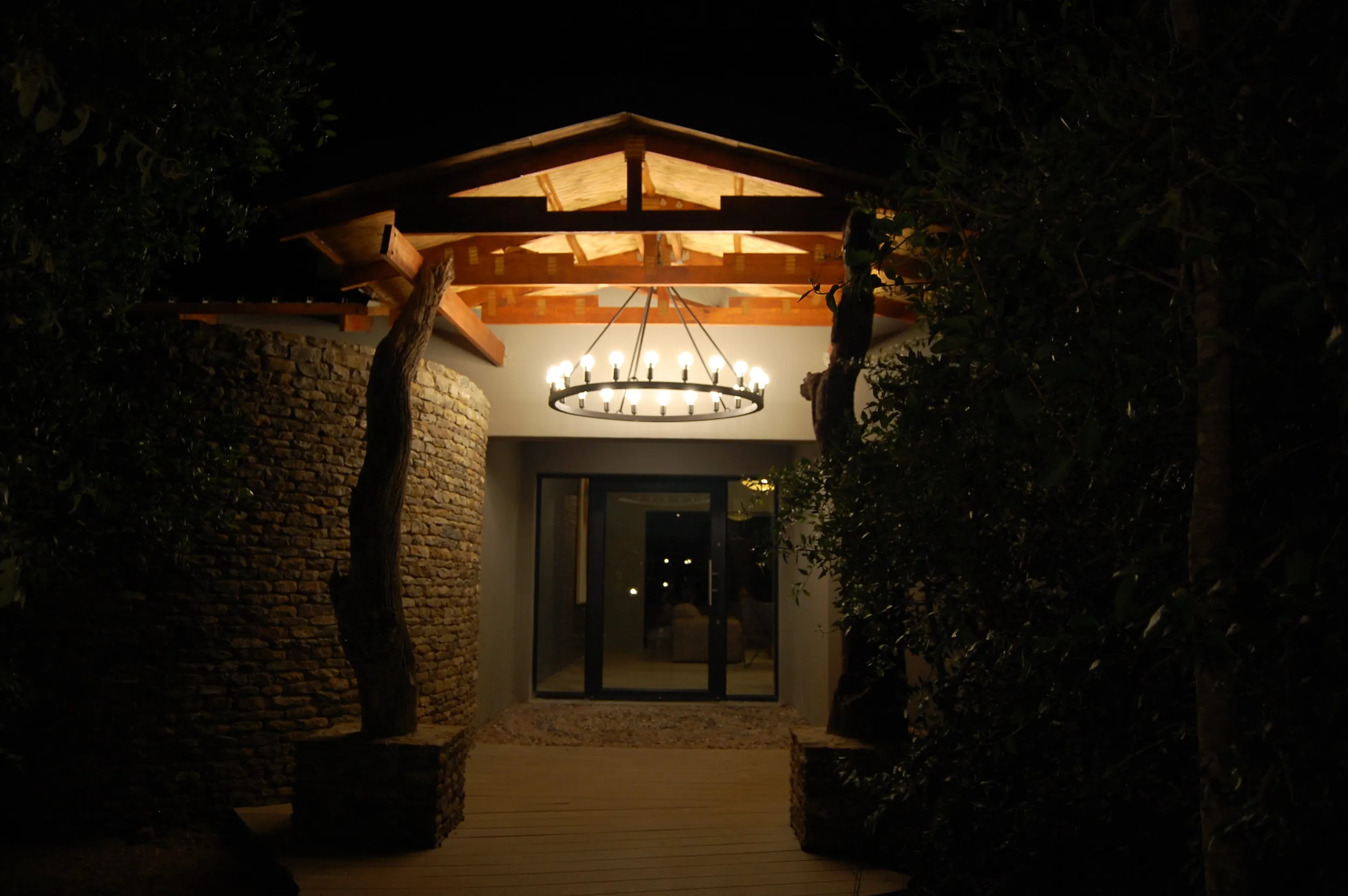 Entrance with illuminated chandelier above door at night surrounded by trees