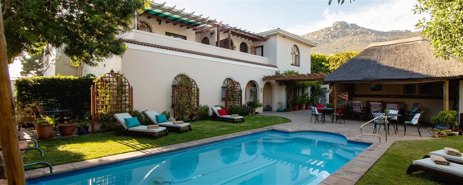 Outdoor pool area with lounge chairs house and mountain view in background