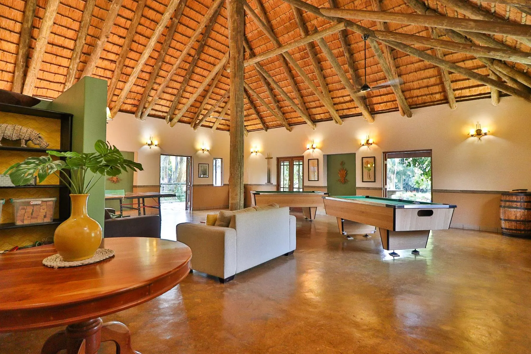 Wooden interior with pool table sofa and potted plant in a spacious room