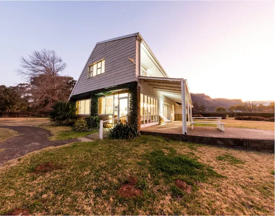 Modern house with large windows and a porch surrounded by grass and trees