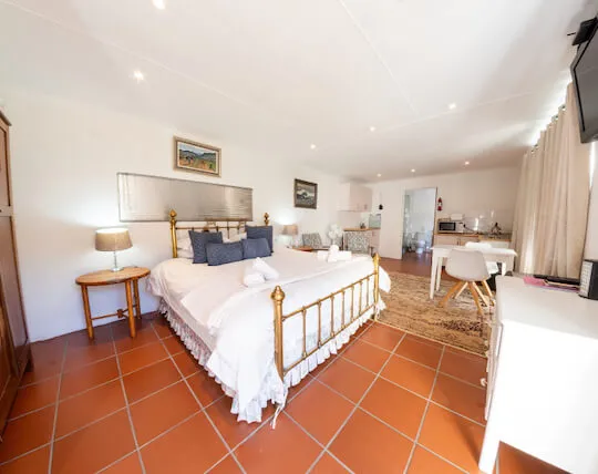 Cozy bedroom with a large bed tiled floor and adjacent kitchenette