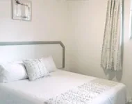 White bedroom with neatly made bed and floral curtains