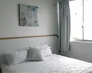 Bright bedroom with white bed pillows and a window with curtains