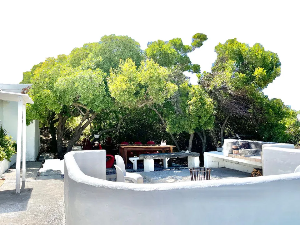 Outdoor seating area with white walls trees and furniture on a patio