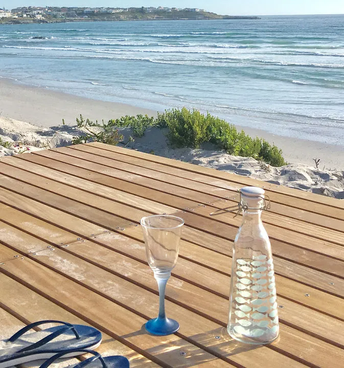 Wooden table with glass and water bottle by beach